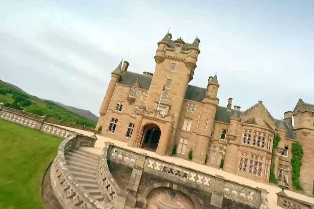 Ardross Castle, a 19th-century sandstone baronial castle with towers, seen from its terraced lawn in the Scottish Highlands
