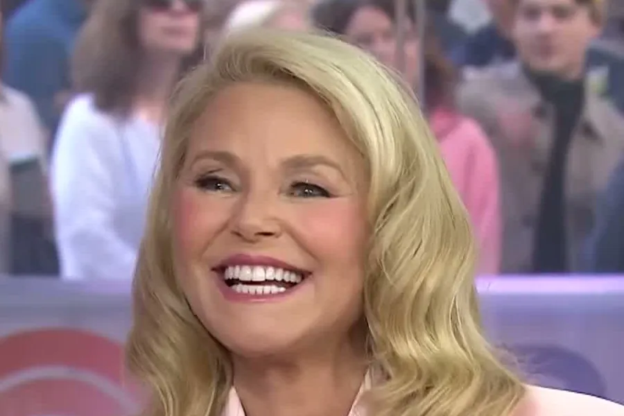 Christie Brinkley with long wavy blond hair in a light pink blazer laughing on the TODAY plaza set