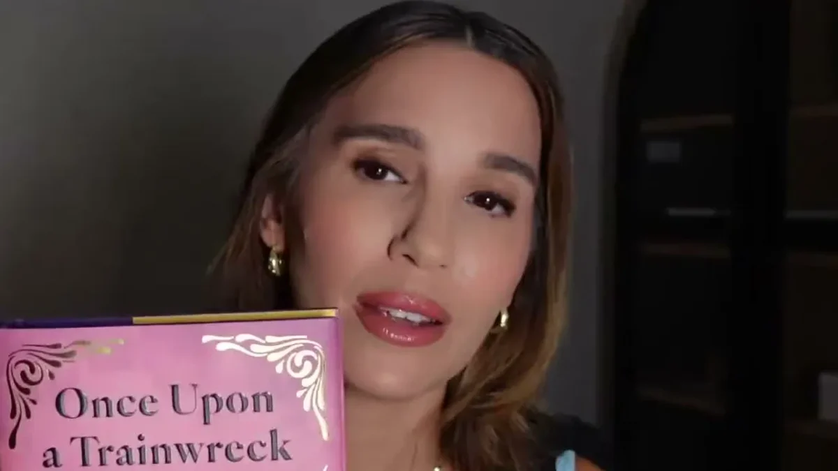 Christy Carlson Romano holding a pink copy of her memoir Once Upon a Trainwreck