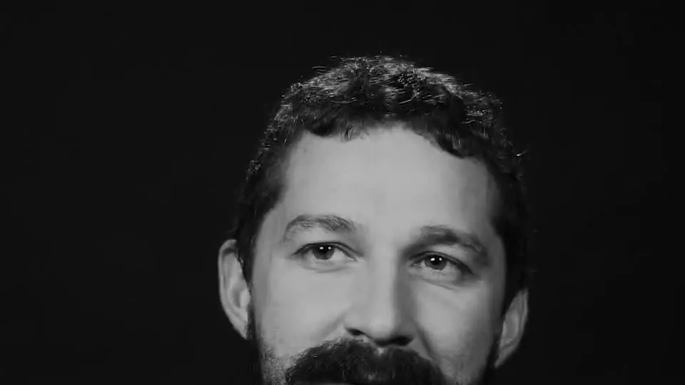 Shia LaBeouf with a beard looking into the camera in a black-and-white portrait