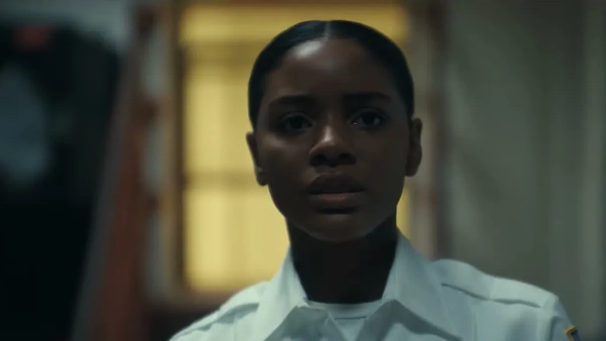Naomi Baker as Anika in a white corrections officer uniform shirt inside a prison