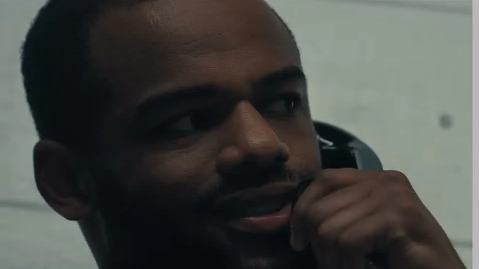 Jay Reeves as Carousel smiling while talking on a prison phone