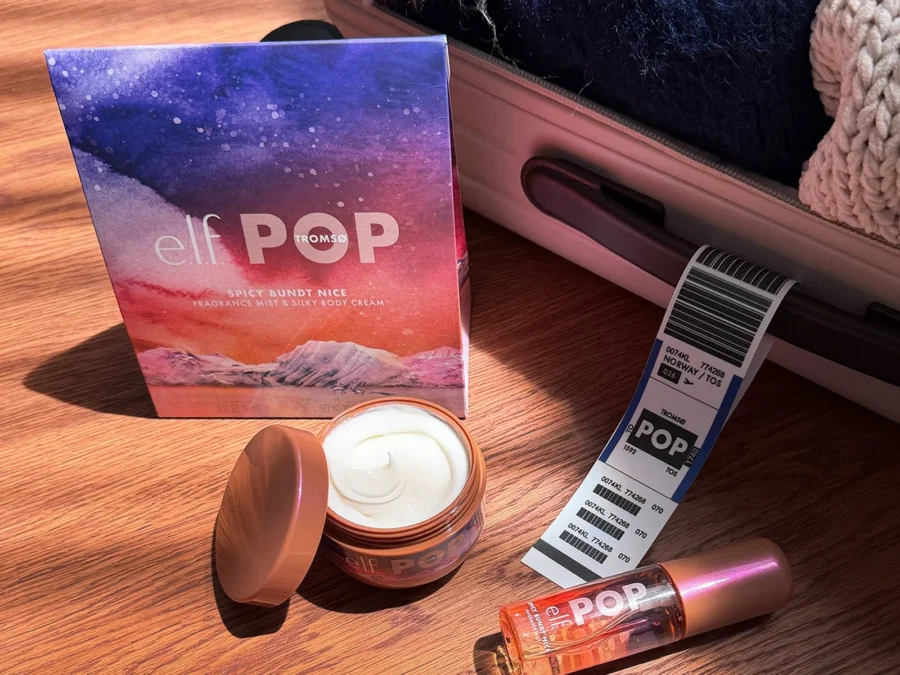 The e.l.f. POP Taste of Tromsø kit box on a wooden floor next to an open mini body cream, a mini fragrance mist and a luggage tag