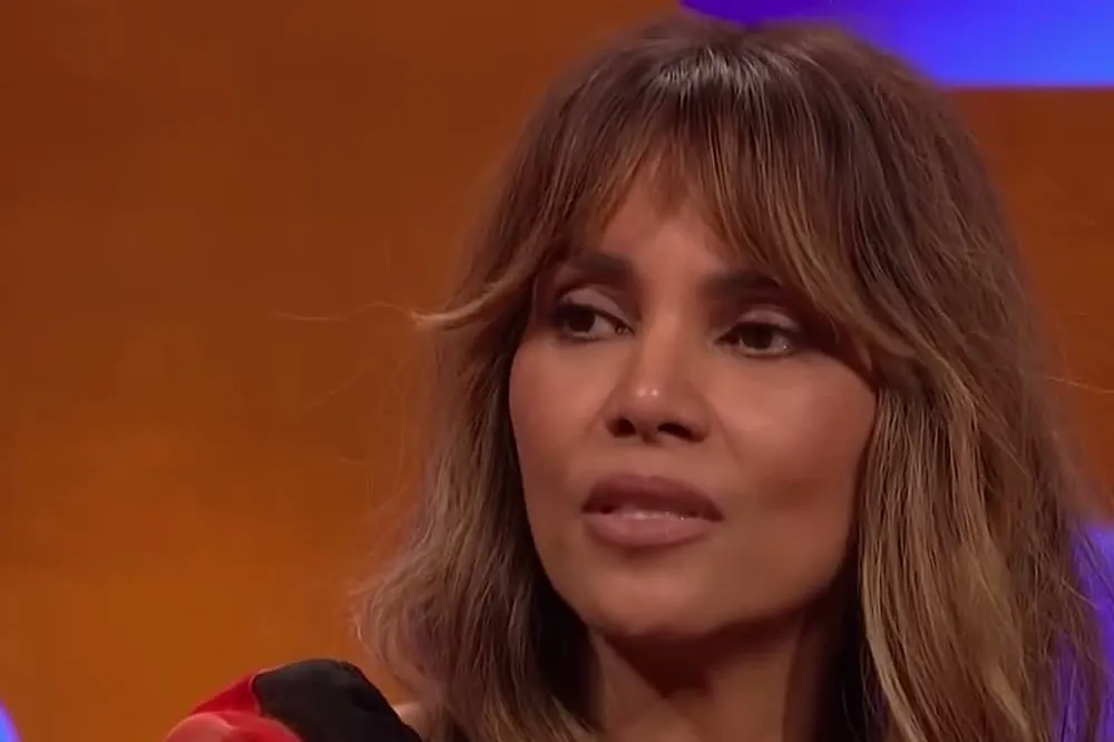 Halle Berry with long highlighted hair and bangs listening on the Graham Norton Show set