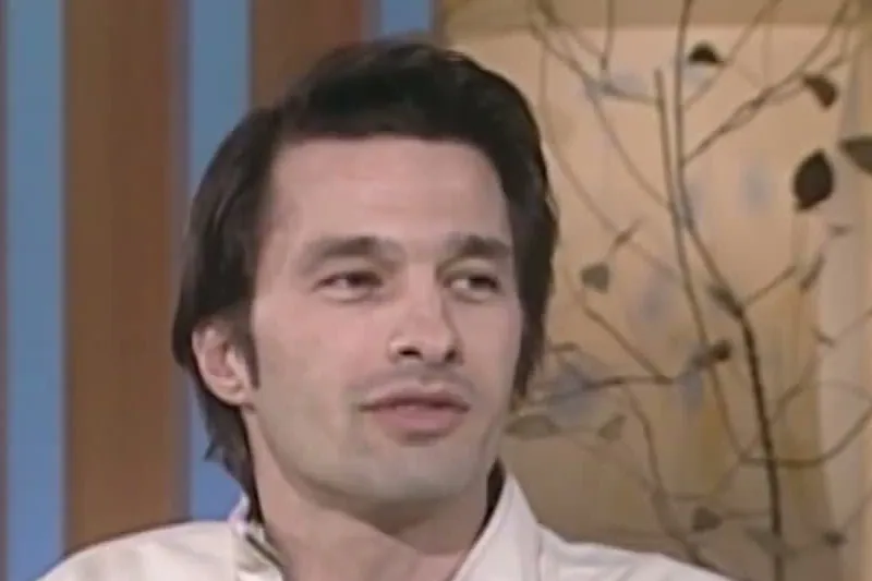 Olivier Martinez with slicked-back dark hair and a white jacket smiling on The Ellen DeGeneres Show set