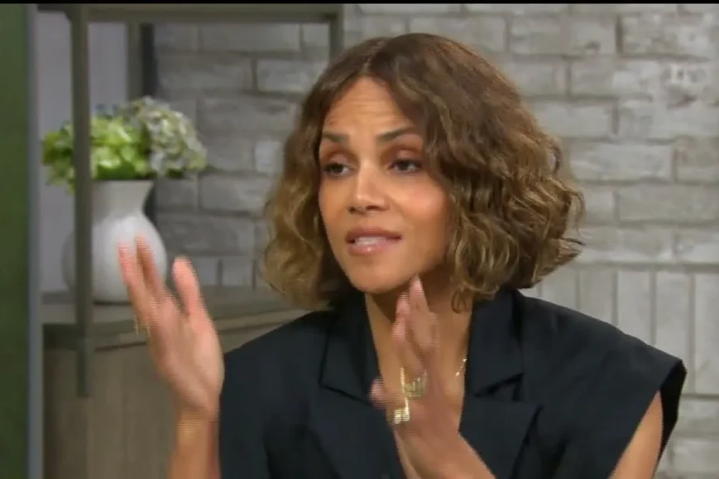 Halle Berry with a short wavy bob in a black sleeveless blazer talking with her hands on CBS Mornings