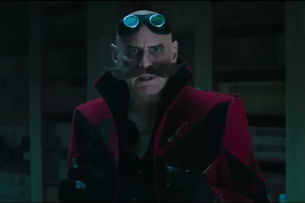 Jim Carrey as Dr. Robotnik with goggles on his bald head, a large mustache and a red coat in a dark library
