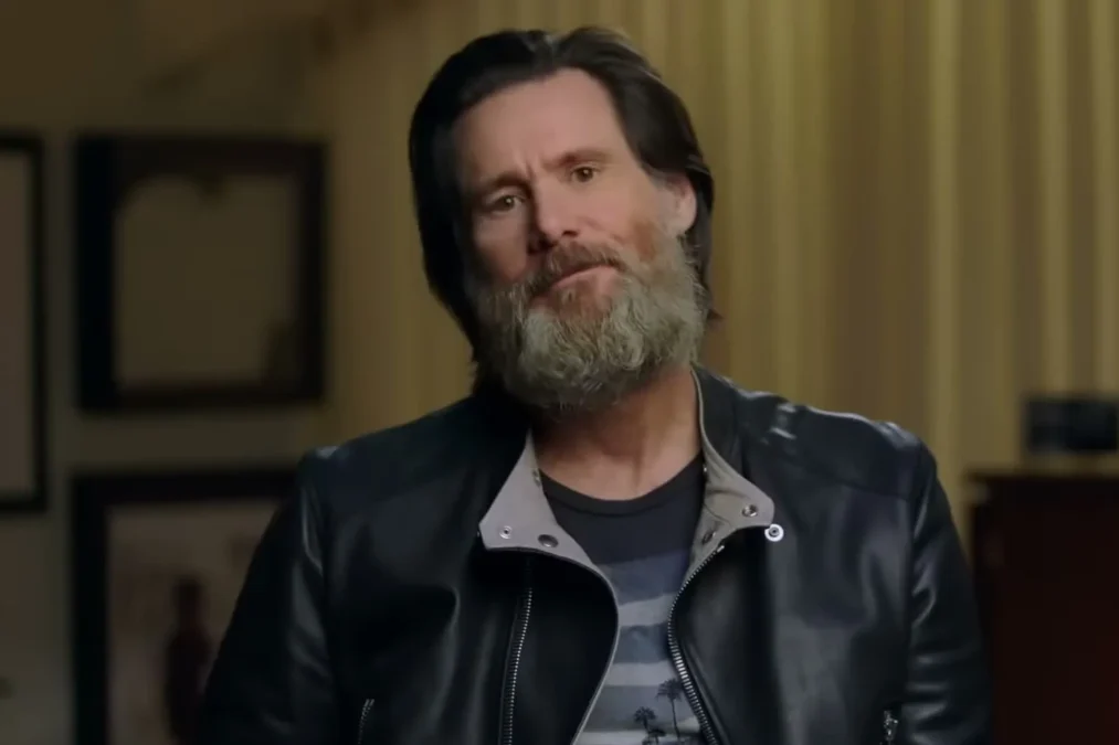 Jim Carrey with a gray beard in a black leather jacket sitting in an interview setting in Jim & Andy