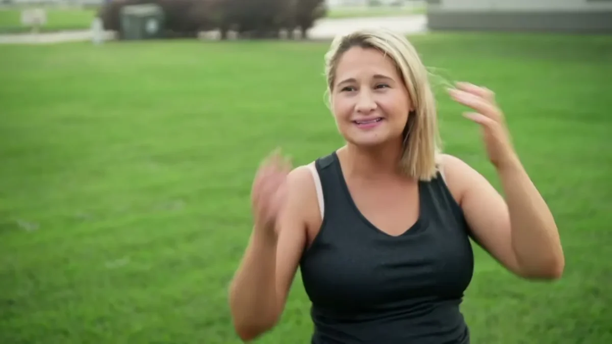 Gypsy Rose Blanchard in a dark tank top smiling and pushing her hair back on a lawn