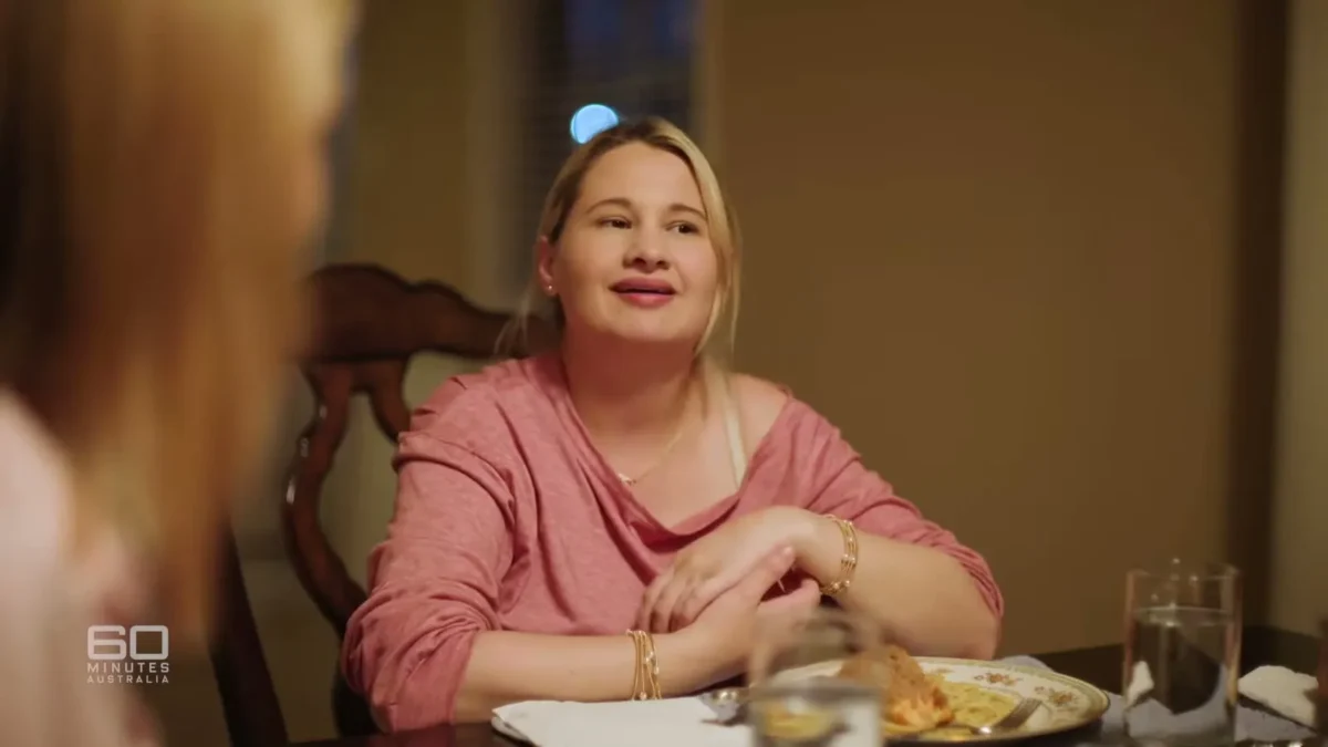 Gypsy Rose Blanchard in a pink top at a dinner table looking up and to the left