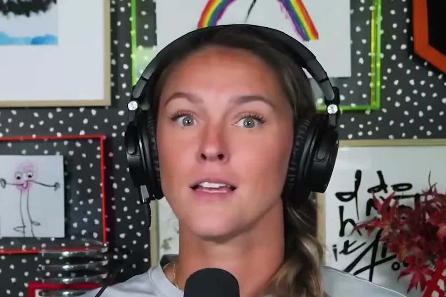 Kylie Kelce with a braid and black headphones raising her eyebrows while talking on the Not Gonna Lie set