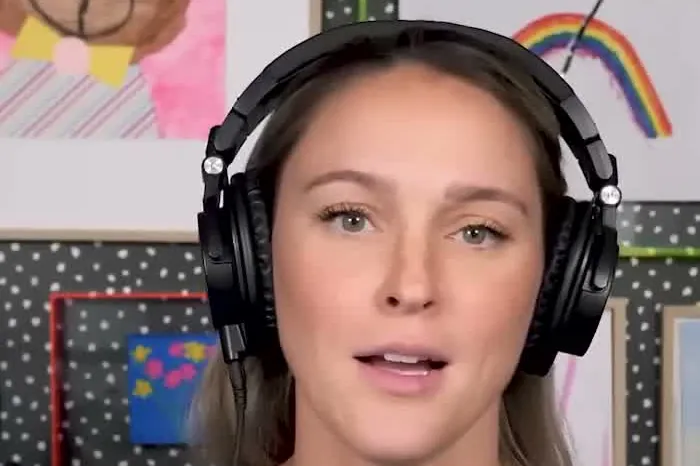 Kylie Kelce with headphones and long hair in a gray sweatshirt at the Not Gonna Lie microphone