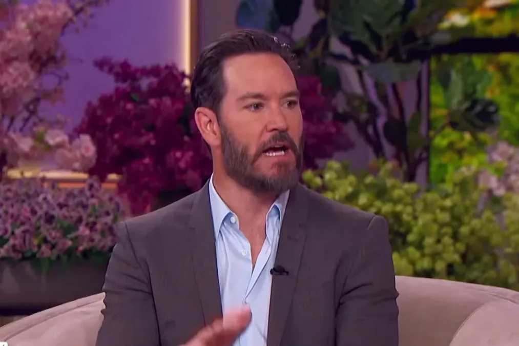 Mark-Paul Gosselaar in a gray blazer and light blue shirt speaking on The Jennifer Hudson Show