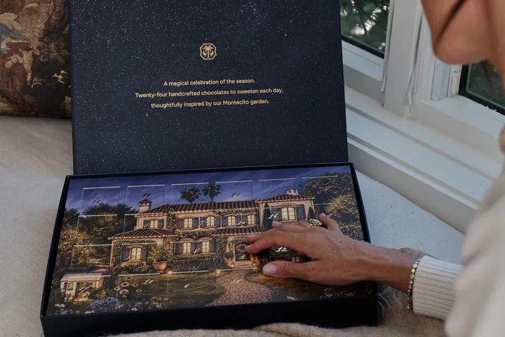 The open As ever advent calendar box with a starry navy lid and an illustrated house on the tray, with a hand on one door