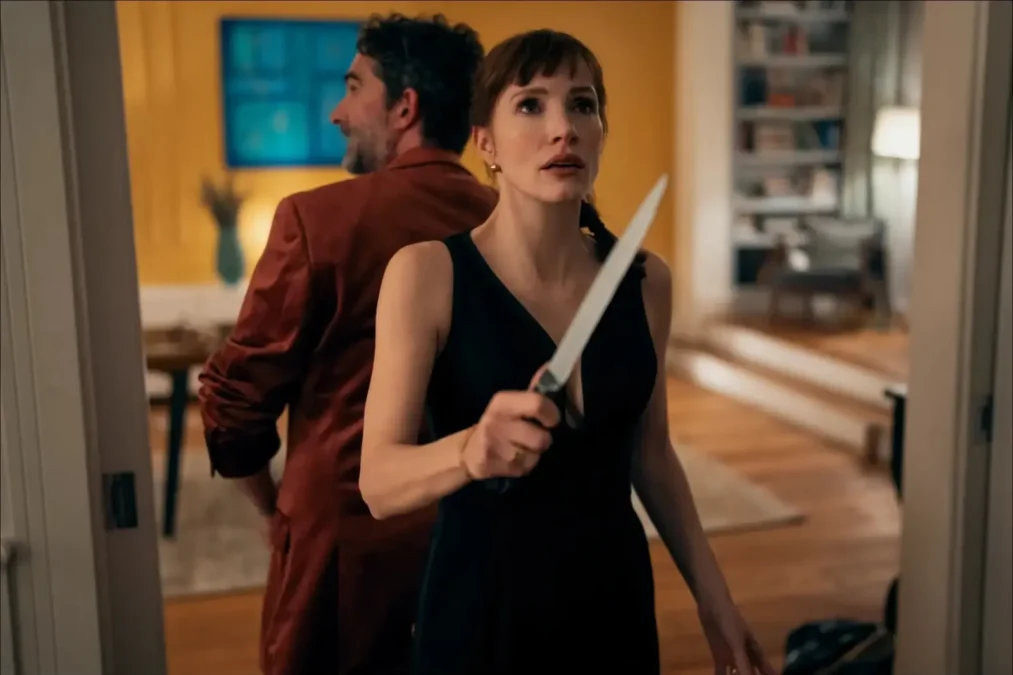 Jessica Chastain in a black dress holding a kitchen knife in a doorway, with a man in a red jacket behind her