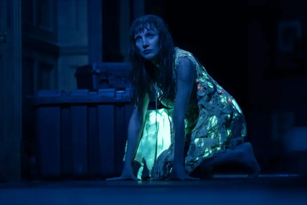Jessica Chastain on her hands and knees in a dark room, lit from below by a glowing blue light