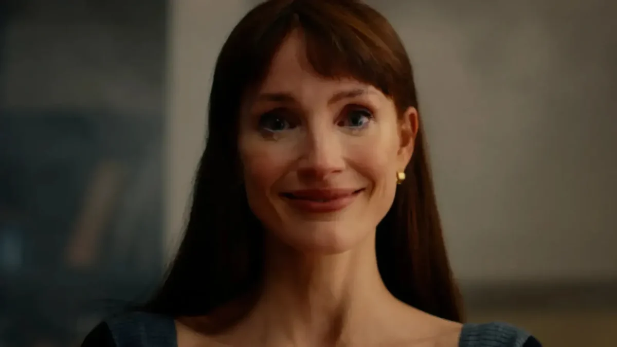 Jessica Chastain with long auburn hair and bangs smiling wide, with a tear on her cheek, in a still from Other Mommy