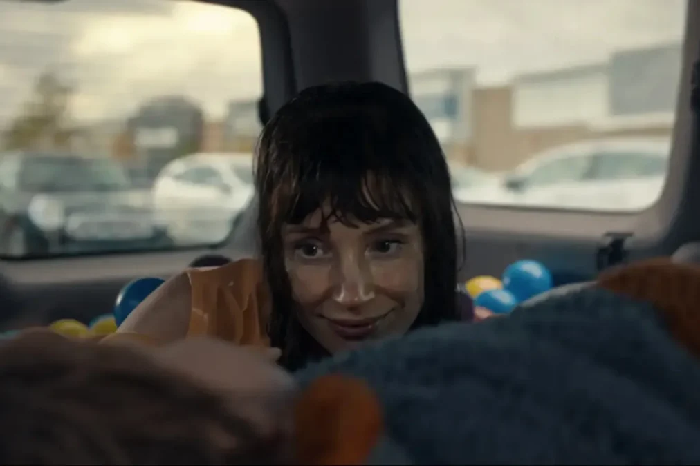 Jessica Chastain with wet hair grinning from the back of a car filled with colored plastic balls