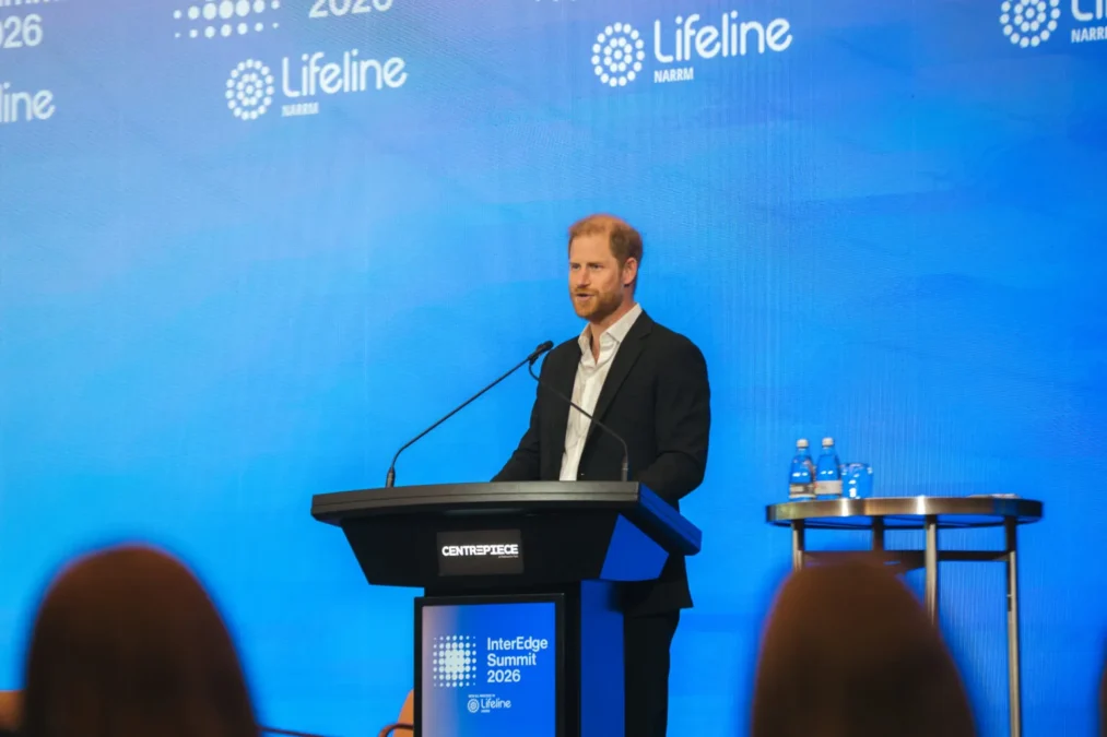 Prince Harry speaking at a lectern in front of a blue Lifeline backdrop