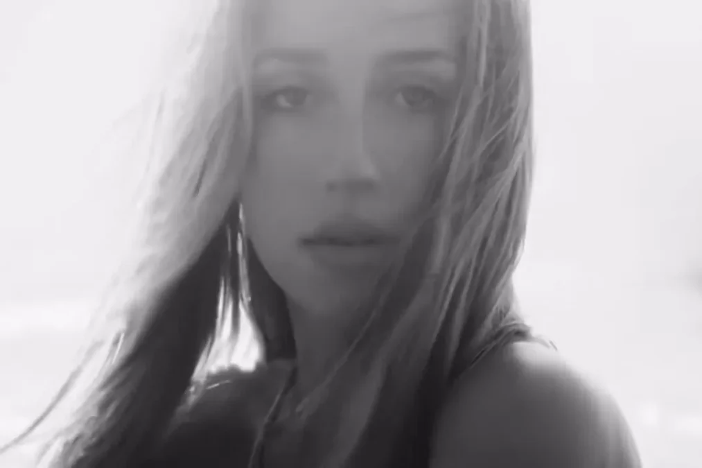 Black-and-white close-up of Tate McRae looking at the camera with strands of hair across her face