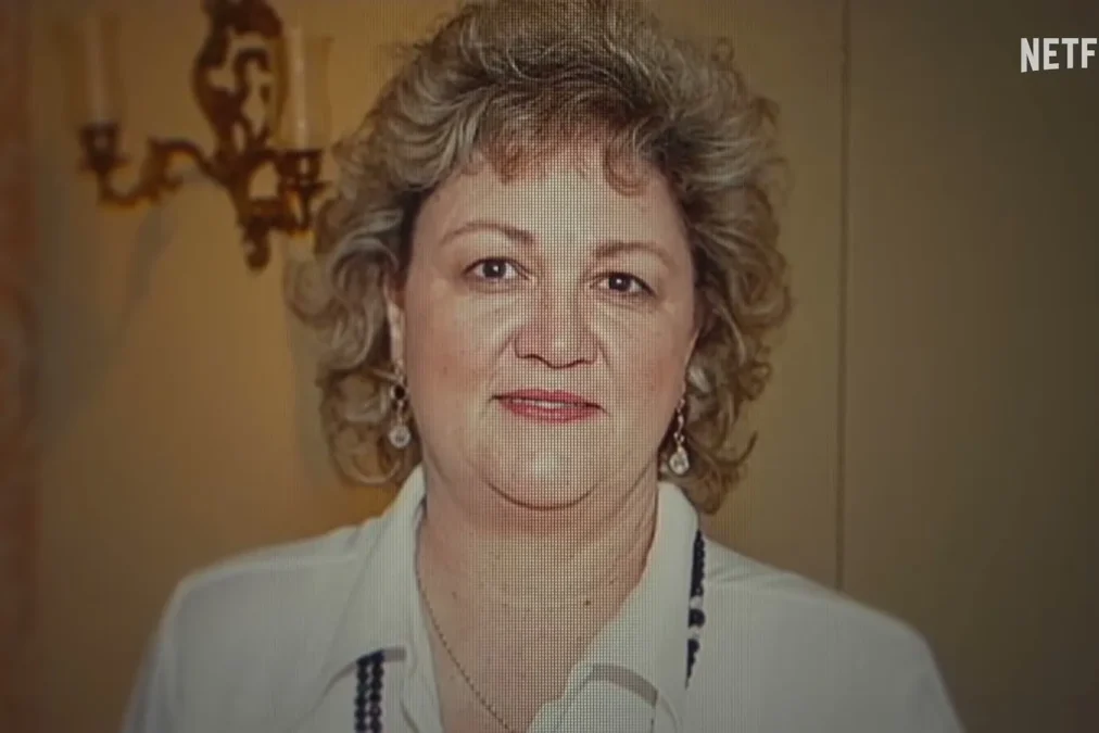 Sharon Causse, a woman with curly reddish-blond hair, earrings and a white blouse, smiling in a portrait