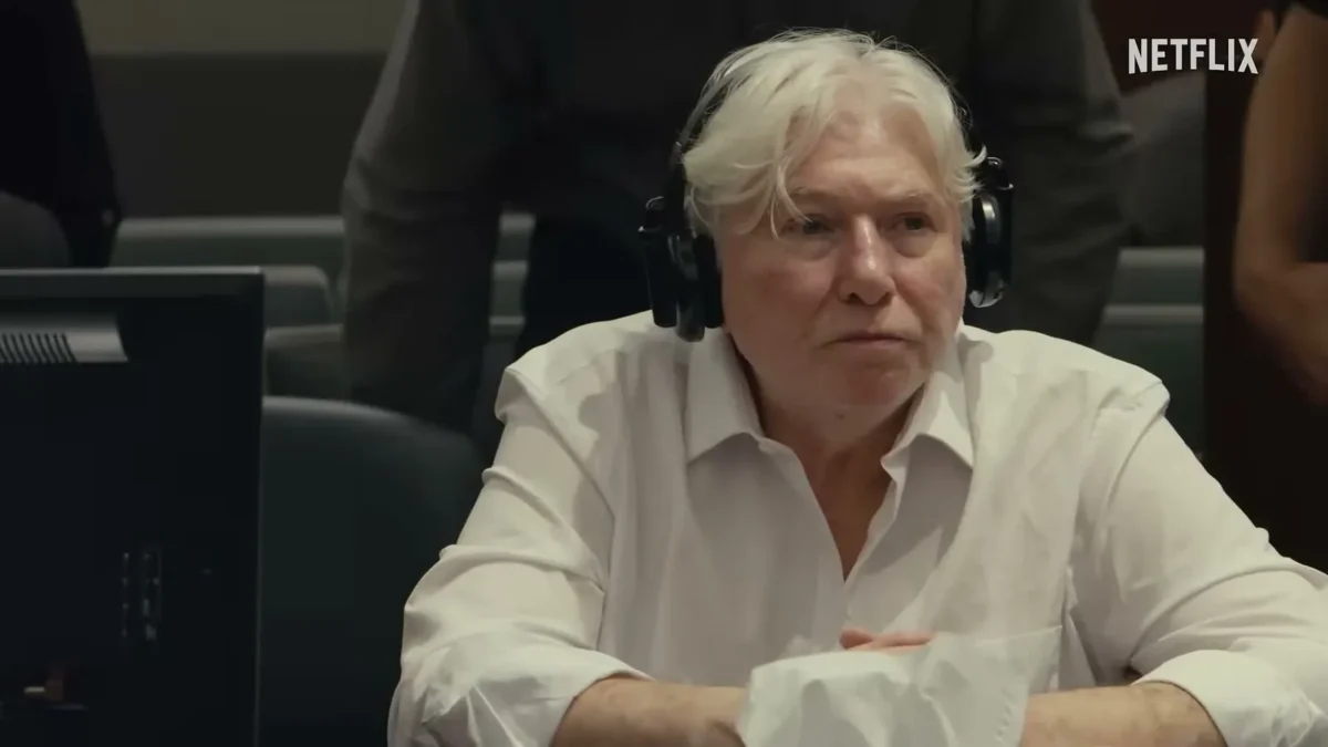 Thomas Randolph, white-haired, in a white shirt and headphones, seated in a courtroom