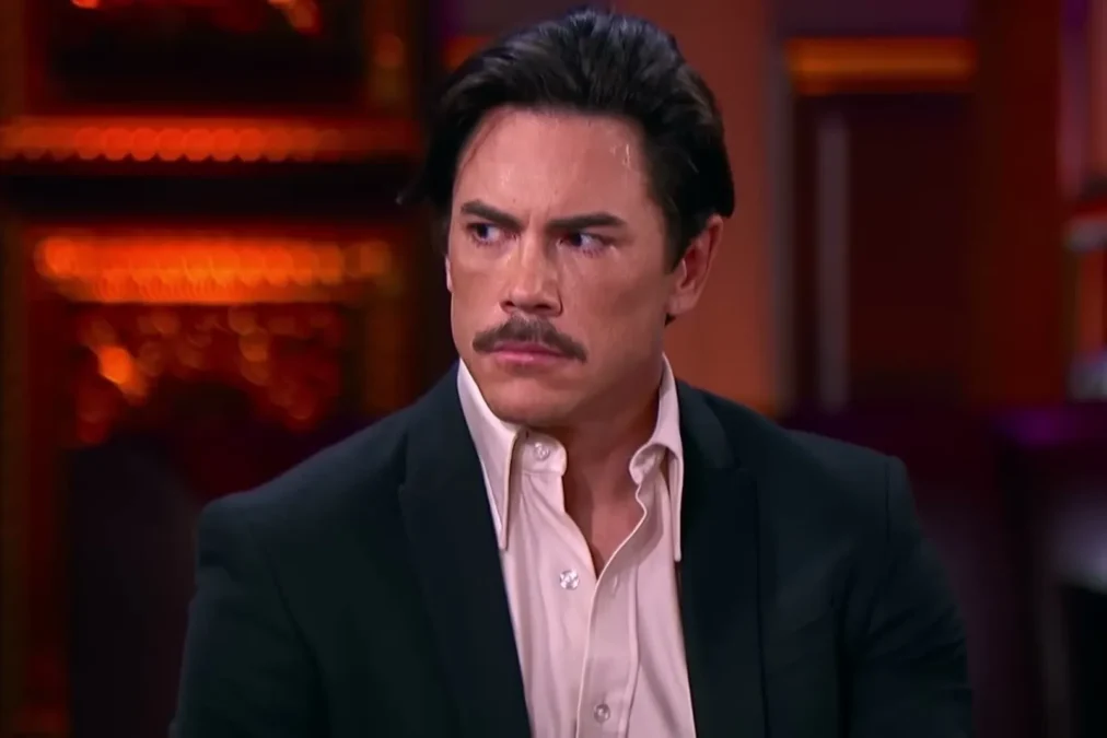 Tom Sandoval with a mustache, in a dark blazer and pink shirt, at the Vanderpump Rules reunion
