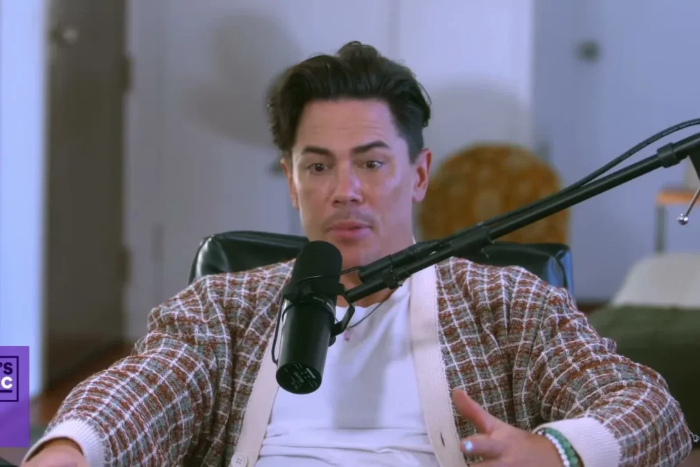 Tom Sandoval in a plaid jacket speaking into a microphone on a podcast set