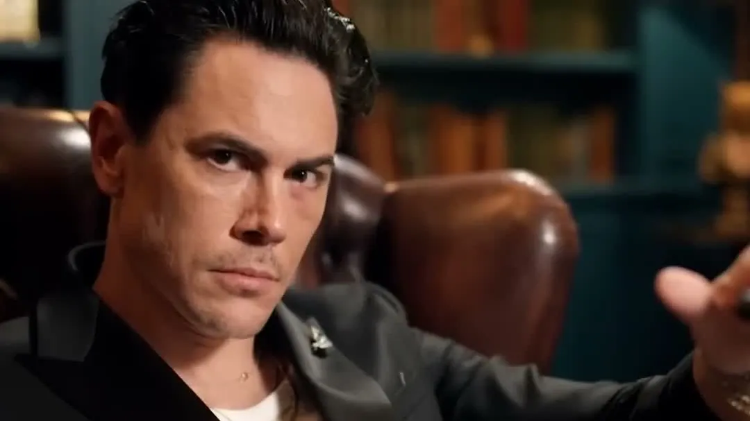 Tom Sandoval in a black jacket sitting in a leather armchair in a library