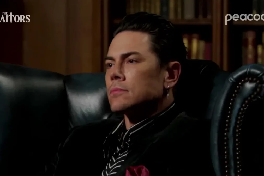 Tom Sandoval in a dark velvet jacket and striped shirt in a leather armchair