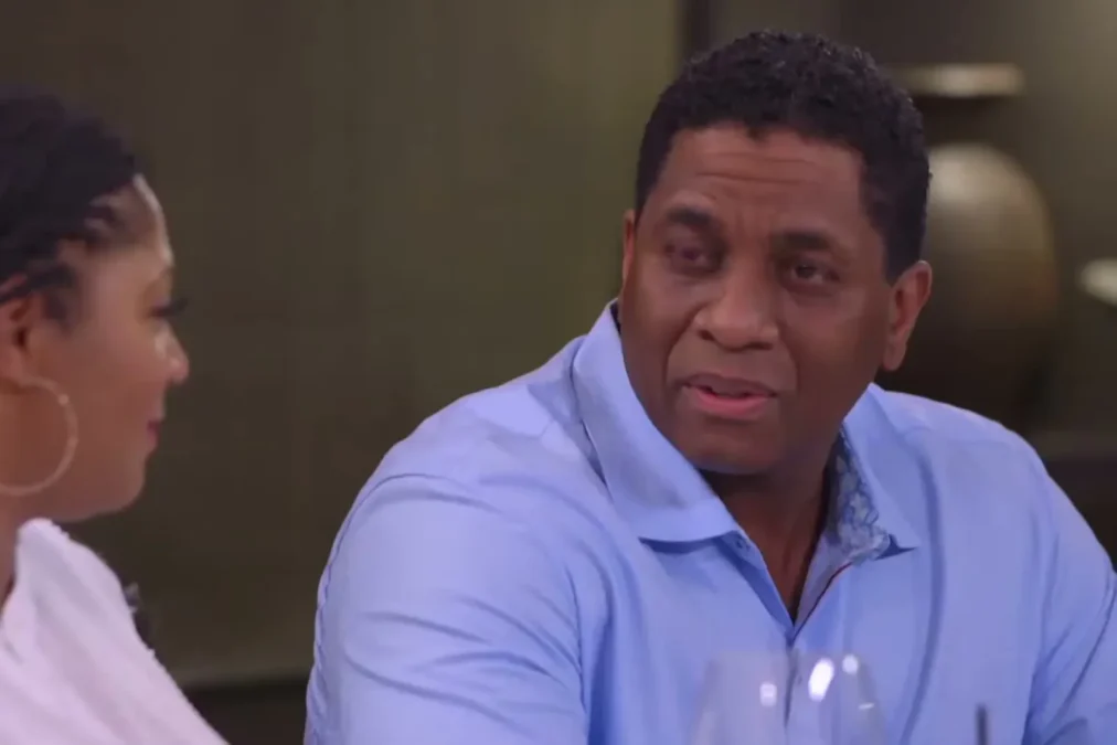 Trina Braxton in profile on the left and Von Scales in a light blue polo shirt seated at a restaurant table in Braxton Family Values